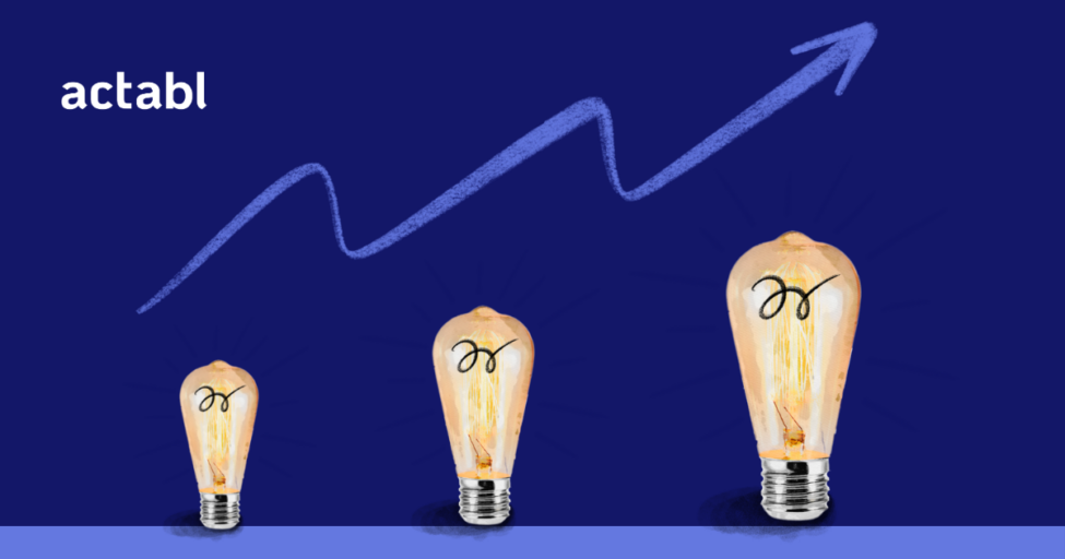 Three light bulbs of increasing size are aligned left to right against a dark blue background. Above them, a zigzag arrow goes upward. The word actabl appears in white text on the top left.